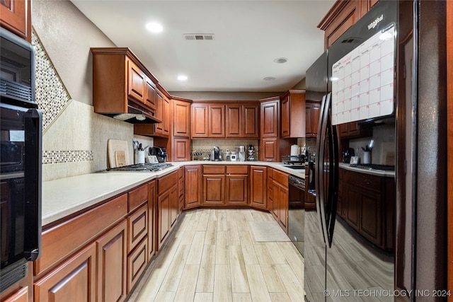 kitchen with backsplash, black appliances, and light wood-type flooring