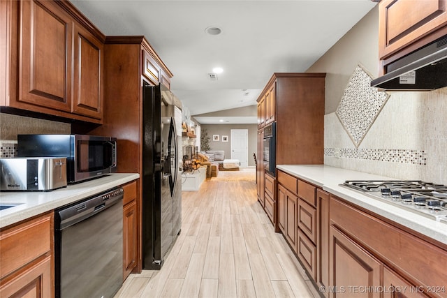 kitchen with range hood, vaulted ceiling, decorative backsplash, black appliances, and light wood-type flooring