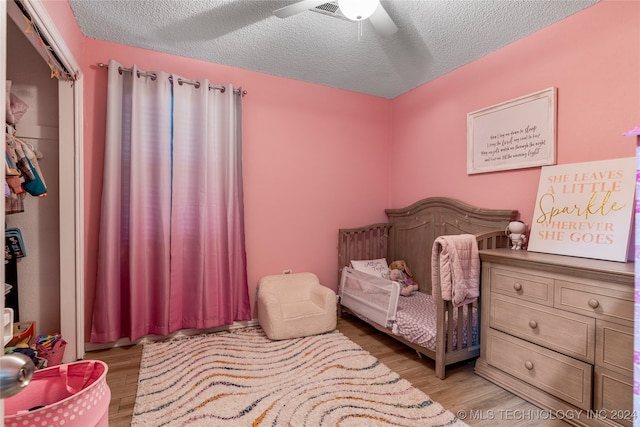 bedroom featuring a textured ceiling, a closet, ceiling fan, and light hardwood / wood-style floors