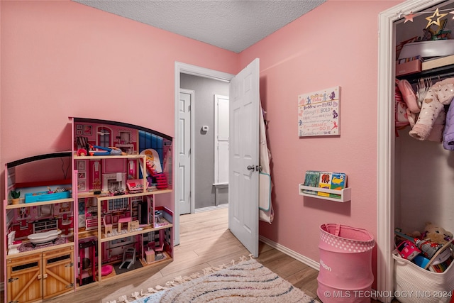 game room with light hardwood / wood-style floors and a textured ceiling