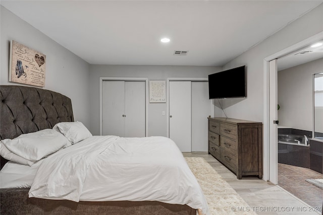 bedroom featuring light hardwood / wood-style floors and multiple closets