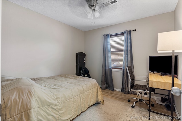 bedroom with ceiling fan, wood-type flooring, and a textured ceiling