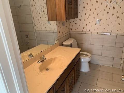 bathroom with tile patterned floors, vanity, toilet, and tile walls