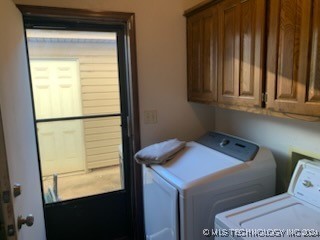 clothes washing area featuring cabinets and separate washer and dryer