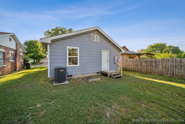 rear view of house featuring central AC and a yard