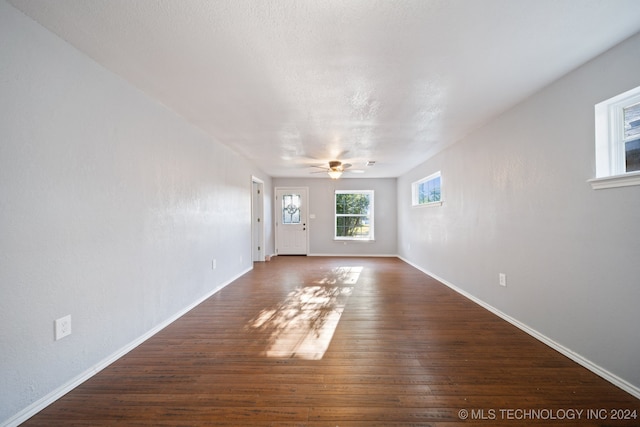 unfurnished living room with ceiling fan and dark wood-type flooring