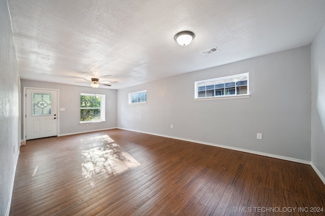 empty room featuring a textured ceiling, dark hardwood / wood-style floors, and ceiling fan