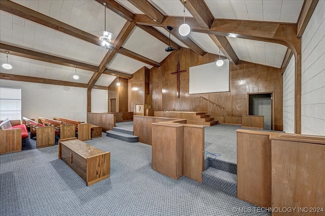 interior space with a kitchen island, lofted ceiling with beams, decorative light fixtures, wooden walls, and carpet