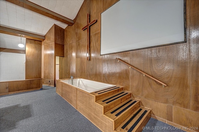 interior space featuring carpet, vaulted ceiling with beams, and wooden walls