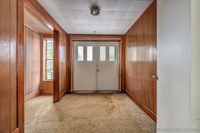 doorway featuring wood walls, french doors, and light colored carpet