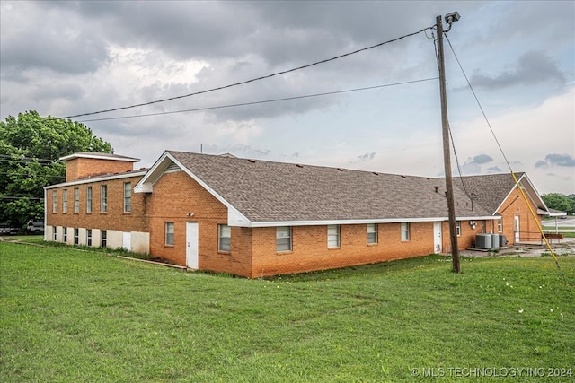 back of property with central air condition unit and a yard