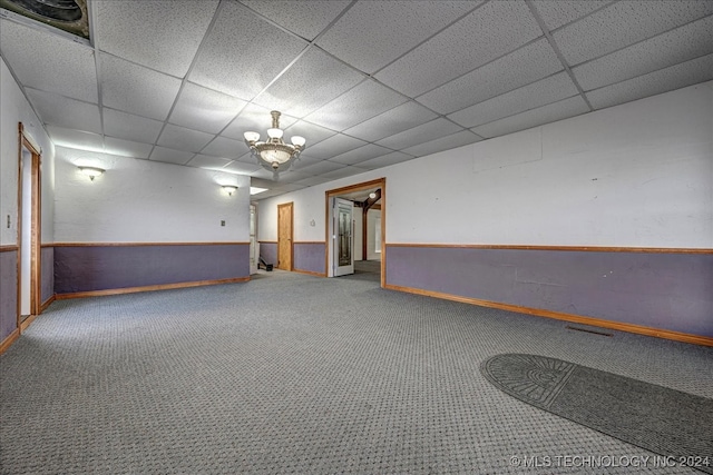 carpeted empty room with a chandelier and a paneled ceiling