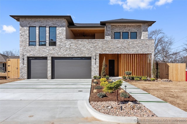 view of front of home with concrete driveway, fence, and stone siding