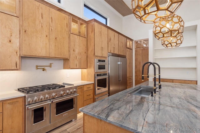 kitchen with light wood finished floors, tasteful backsplash, high quality appliances, light stone counters, and a sink