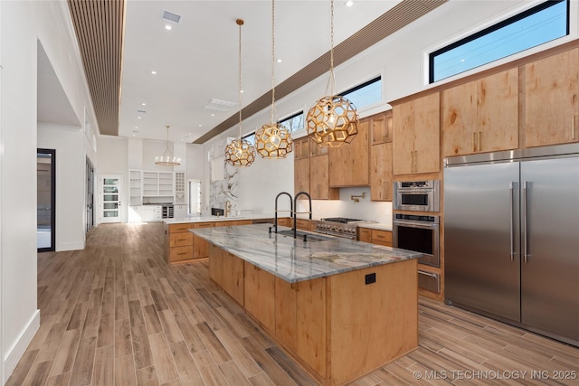 kitchen featuring visible vents, a spacious island, wood finish floors, appliances with stainless steel finishes, and a notable chandelier