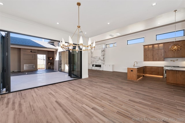 unfurnished dining area featuring a high ceiling, a notable chandelier, wood finished floors, and recessed lighting