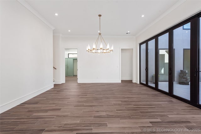 unfurnished dining area featuring baseboards, a notable chandelier, wood finished floors, and ornamental molding