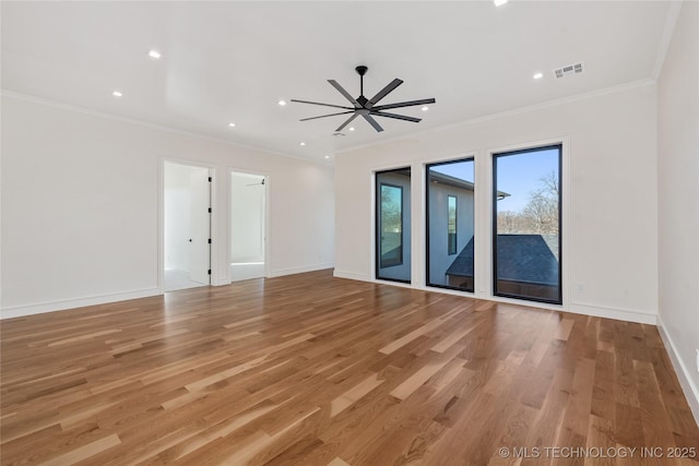 empty room with visible vents, baseboards, ornamental molding, and light wood finished floors