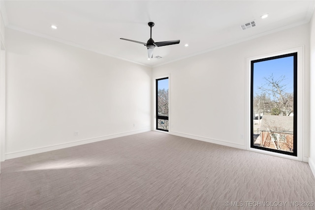 unfurnished room featuring baseboards, visible vents, carpet floors, ceiling fan, and crown molding