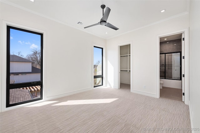 unfurnished bedroom with visible vents, carpet floors, crown molding, baseboards, and a spacious closet