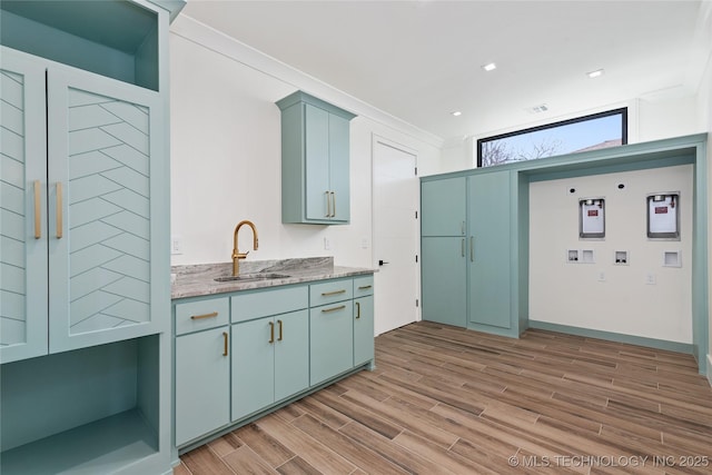 kitchen featuring visible vents, a sink, recessed lighting, light wood-style floors, and light stone countertops