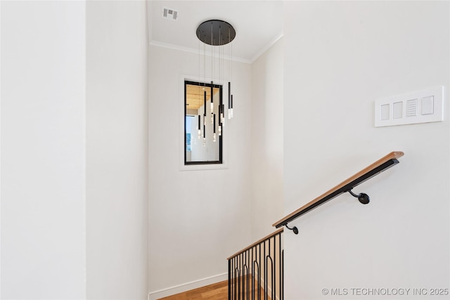 stairway featuring baseboards, wood finished floors, visible vents, and ornamental molding