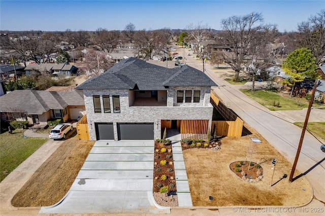 view of front facade featuring a shingled roof, concrete driveway, a garage, stone siding, and a residential view