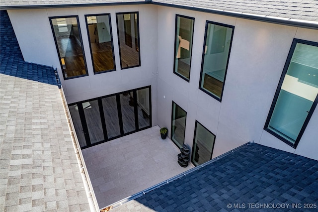 entrance to property with stucco siding and a shingled roof