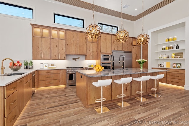 kitchen with wood finish floors, high quality appliances, a breakfast bar area, and a sink