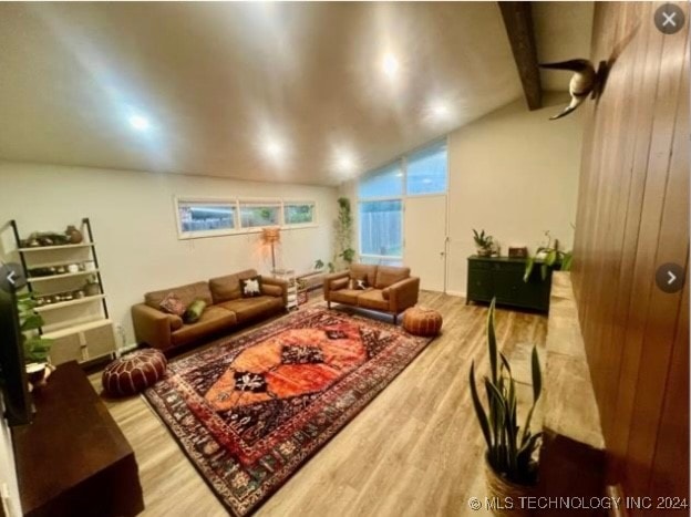 living room featuring wood walls, lofted ceiling with beams, and hardwood / wood-style flooring