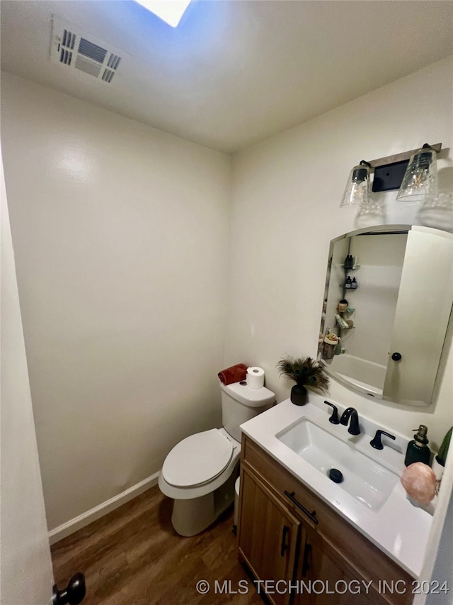 bathroom with wood-type flooring, vanity, and toilet