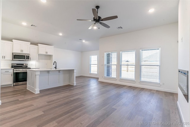 kitchen featuring light hardwood / wood-style flooring, white cabinets, an island with sink, and appliances with stainless steel finishes