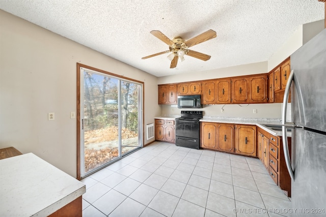 kitchen with black appliances, ceiling fan, light tile patterned flooring, and a textured ceiling