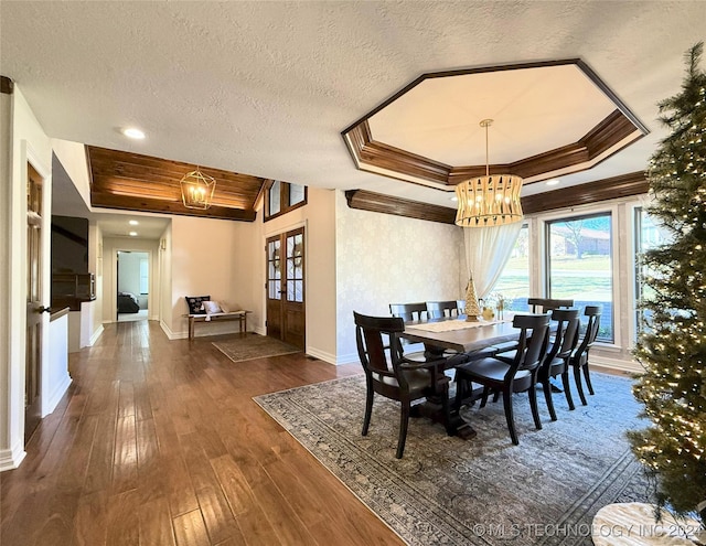 dining space featuring a raised ceiling, dark hardwood / wood-style flooring, a textured ceiling, and an inviting chandelier