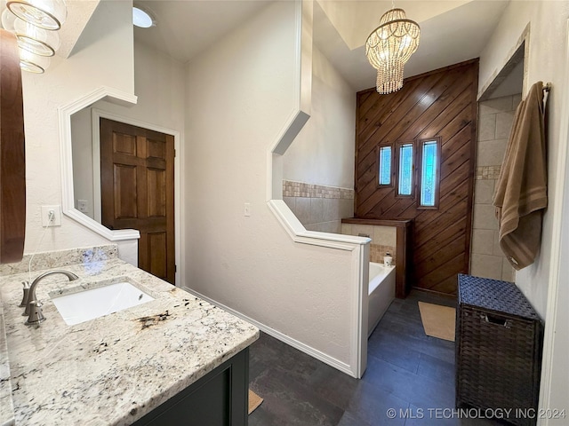 bathroom featuring vanity, a tub to relax in, an inviting chandelier, and wood walls