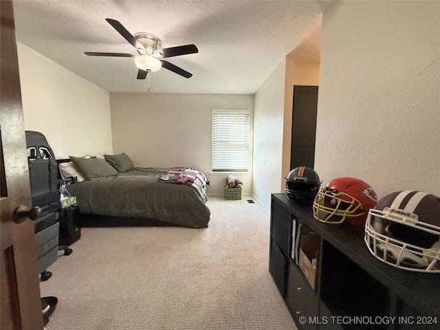 carpeted bedroom featuring ceiling fan and a textured ceiling