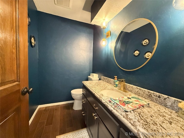 bathroom featuring toilet, vanity, and hardwood / wood-style flooring