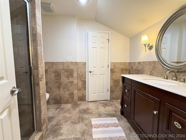 bathroom featuring walk in shower, vaulted ceiling, toilet, vanity, and tile walls