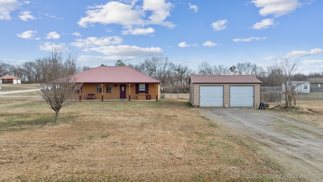 single story home featuring covered porch, a garage, an outdoor structure, and a front yard