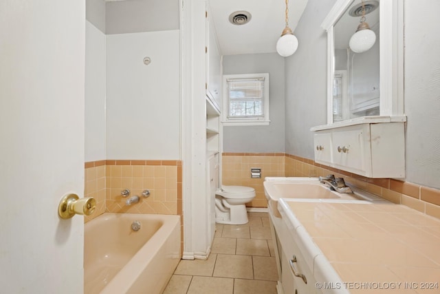 bathroom featuring tile patterned floors, vanity, tile walls, toilet, and a bathing tub