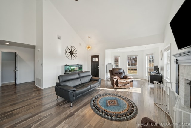 living room featuring wood-type flooring, an inviting chandelier, high vaulted ceiling, and a brick fireplace