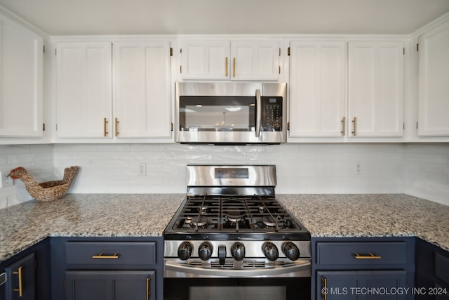 kitchen with light stone countertops, appliances with stainless steel finishes, tasteful backsplash, blue cabinets, and white cabinetry