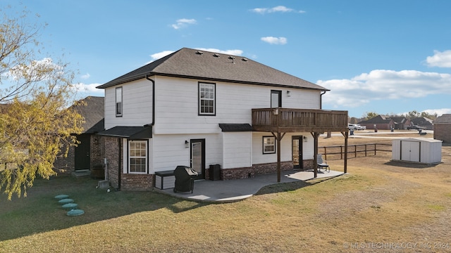 back of property featuring a yard, a deck, a storage shed, and a patio area