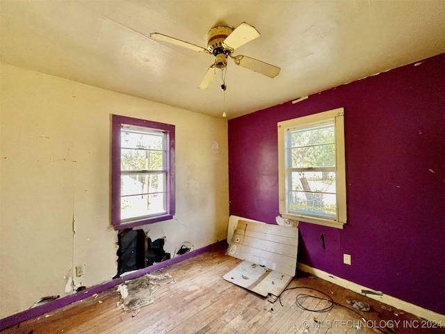 spare room with a wealth of natural light, ceiling fan, and light hardwood / wood-style floors