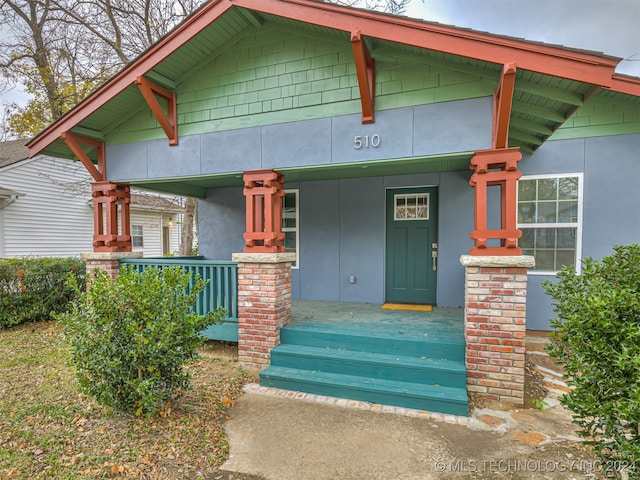 view of exterior entry featuring covered porch