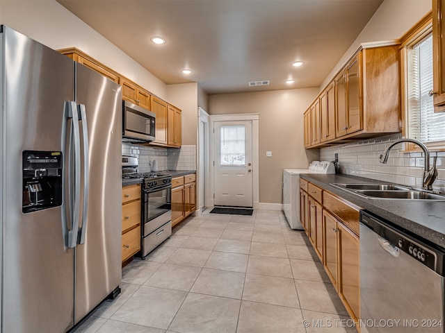 kitchen with sink, light tile patterned floors, tasteful backsplash, stainless steel appliances, and washing machine and clothes dryer