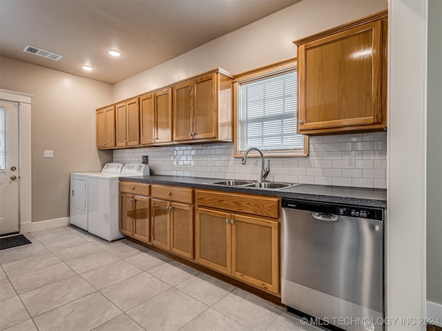 kitchen featuring sink, stainless steel dishwasher, independent washer and dryer, decorative backsplash, and light tile patterned floors