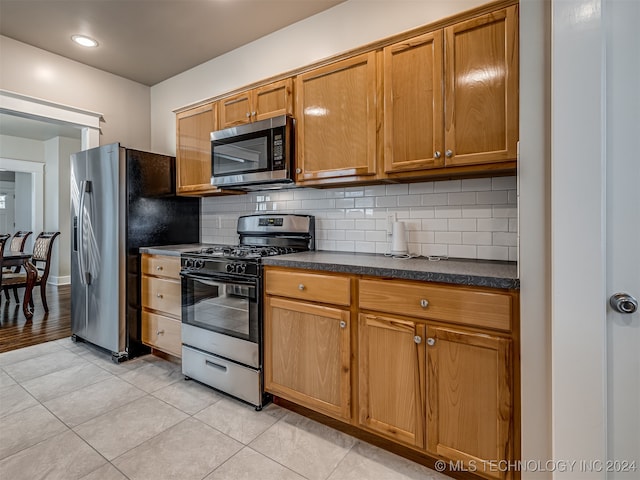 kitchen with appliances with stainless steel finishes, backsplash, and light tile patterned floors