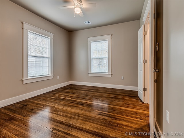 empty room featuring dark hardwood / wood-style flooring, plenty of natural light, and ceiling fan