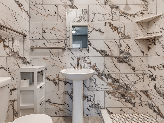 bathroom featuring ceiling fan, toilet, and tile walls